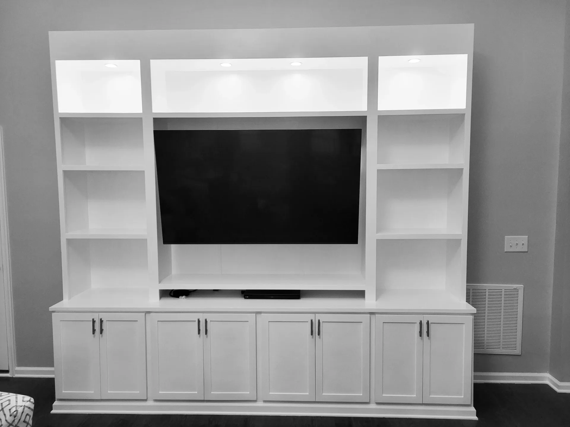 A black and white photo of a entertainment center with a flat screen tv