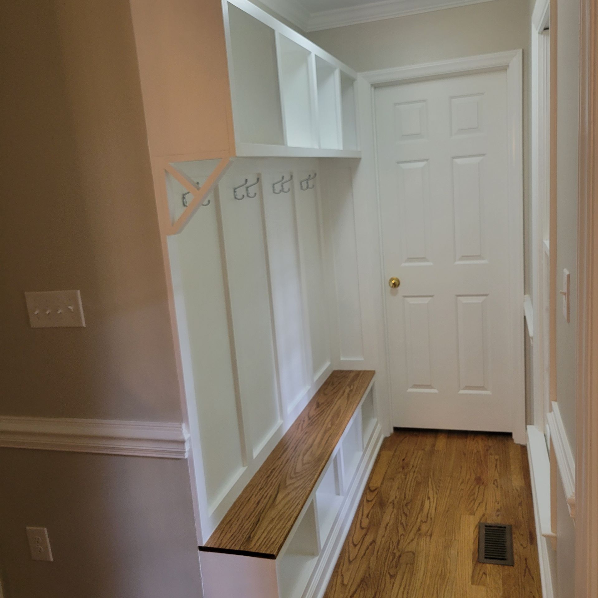 A hallway with a wooden bench and a white door.