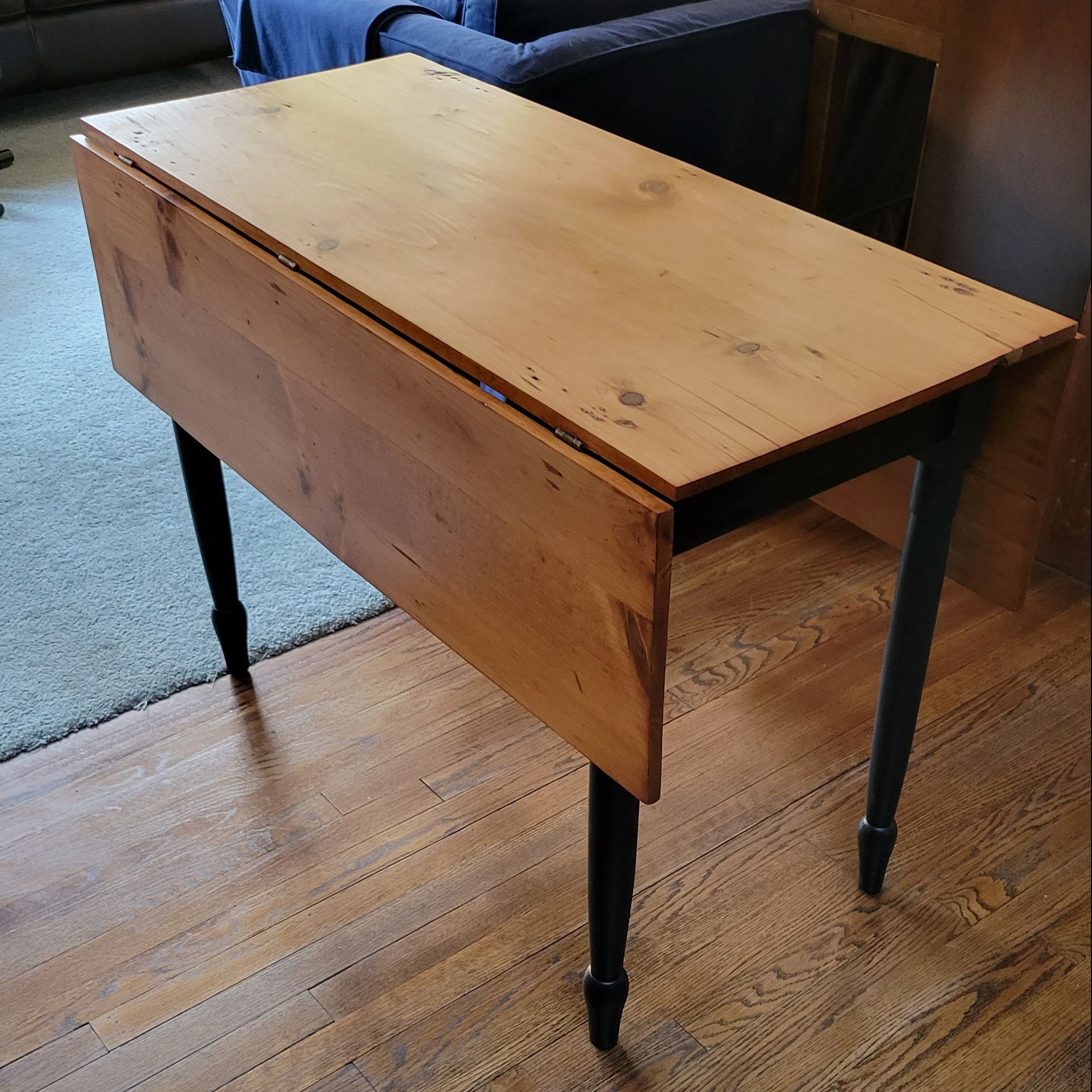 A wooden table with black legs is sitting on a wooden floor