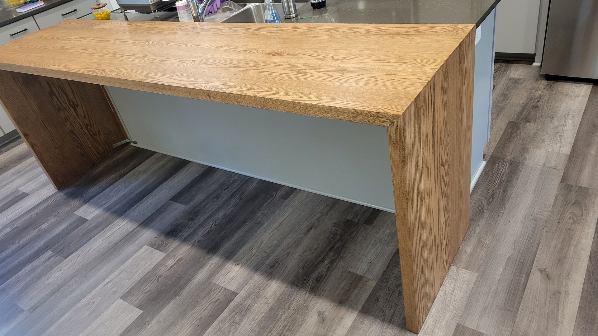 A large wooden table is sitting on top of a wooden floor in a kitchen.