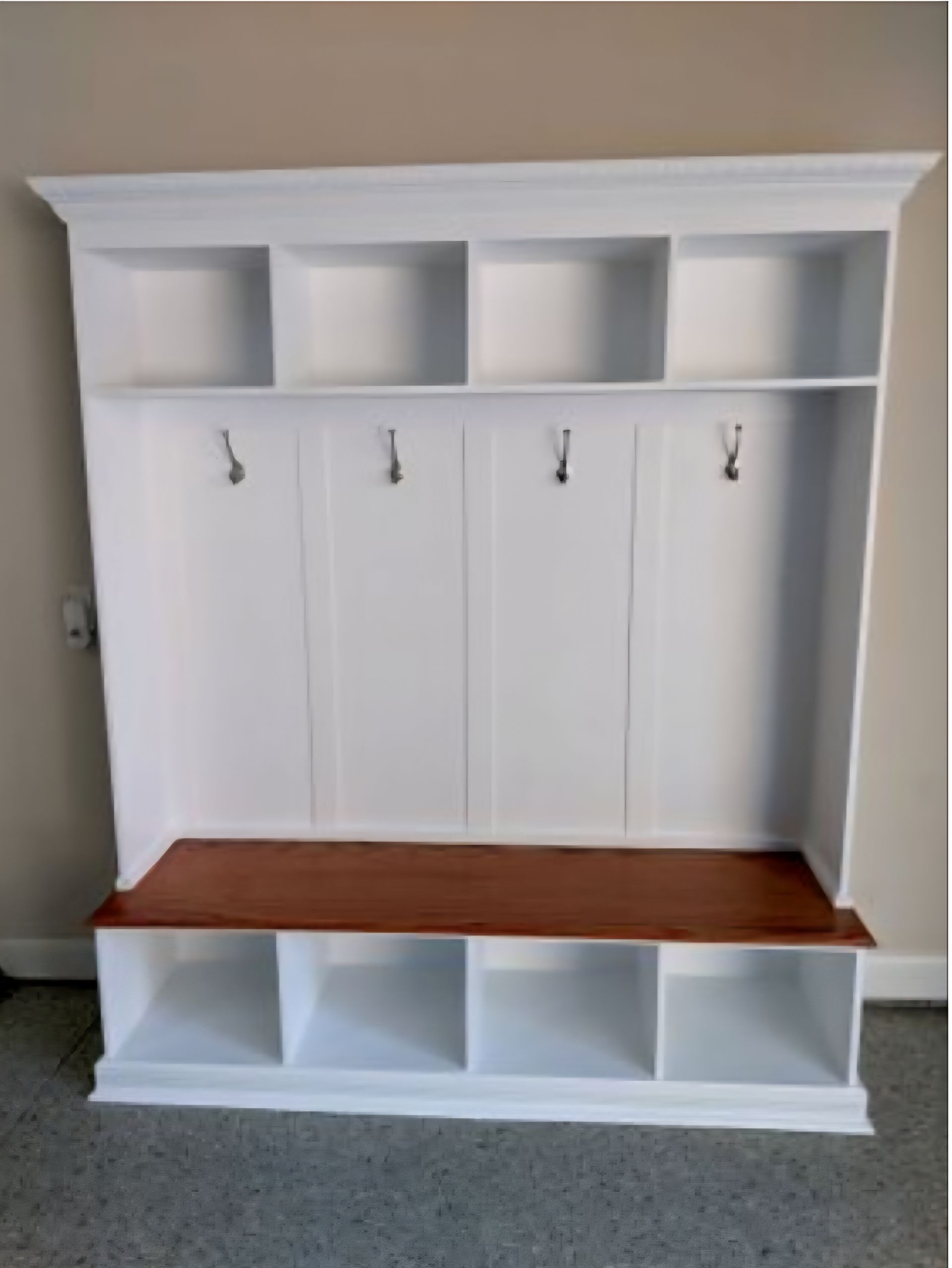 A white coat rack with a wooden bench underneath it.