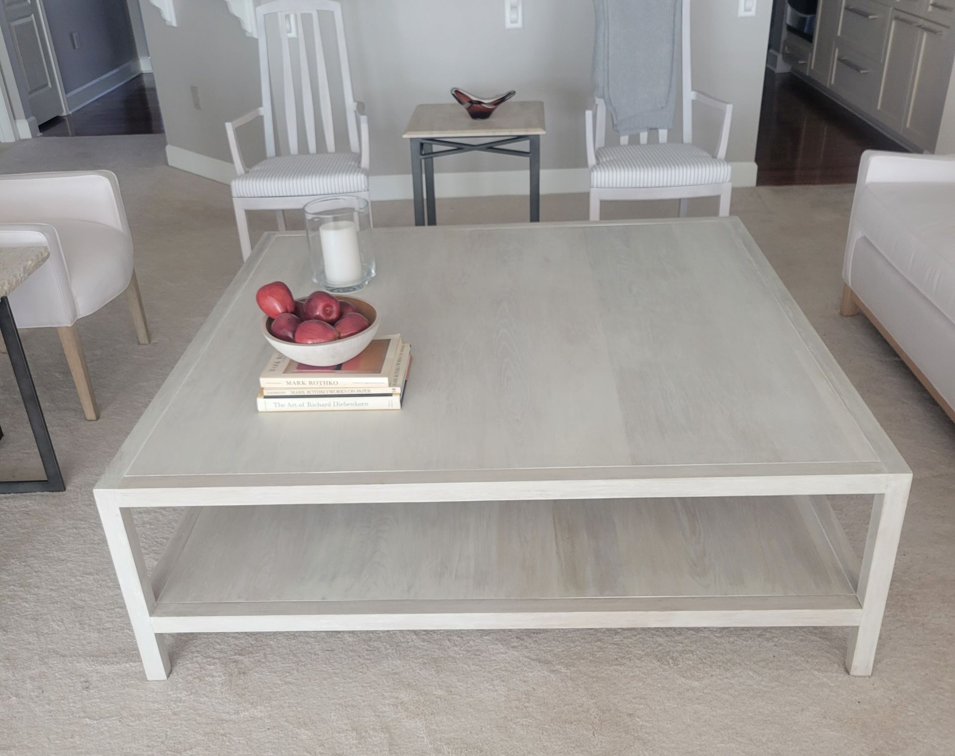 A white coffee table with a bowl of apples on it