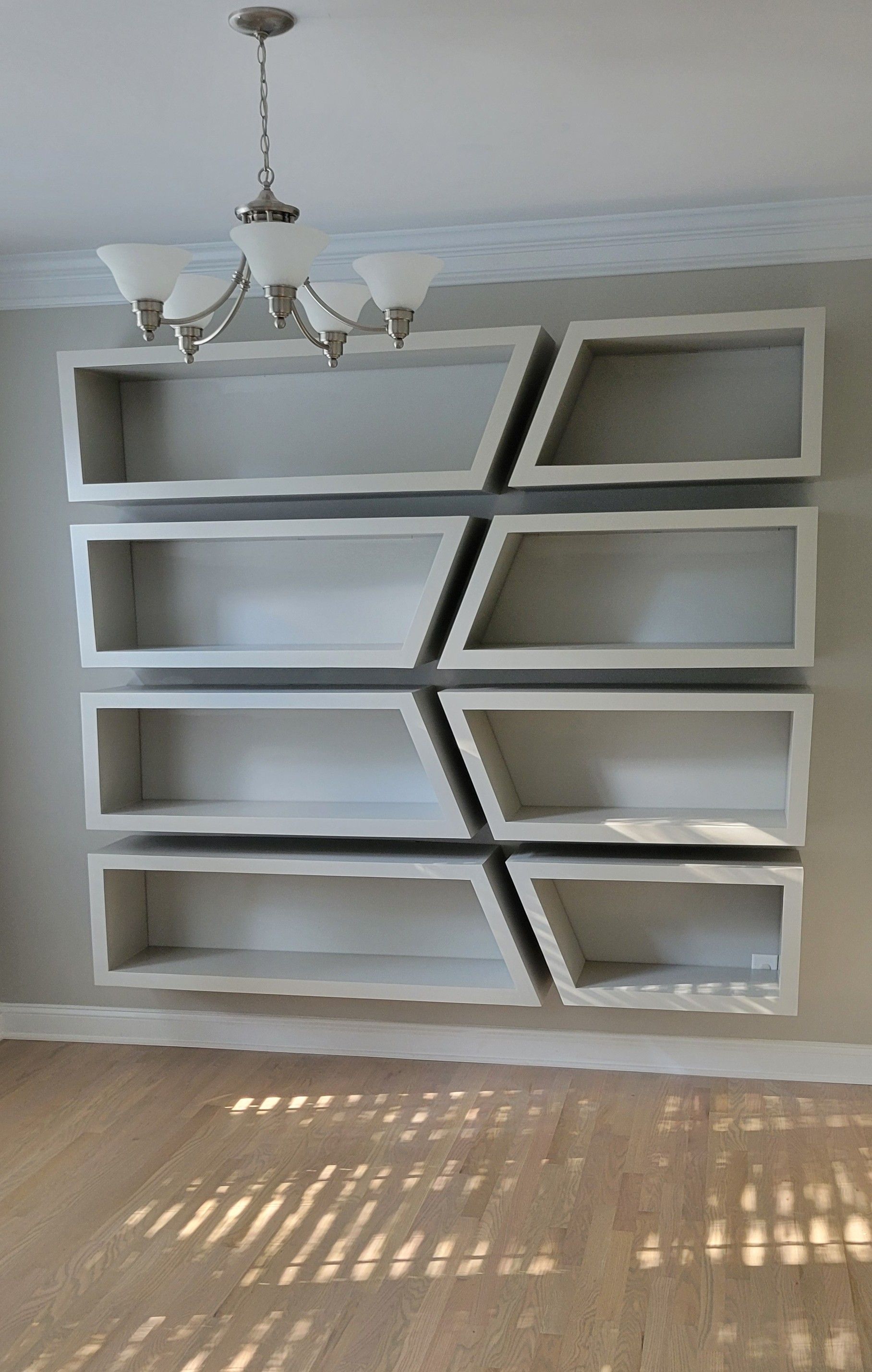 There is a chandelier hanging from the ceiling above the shelves.