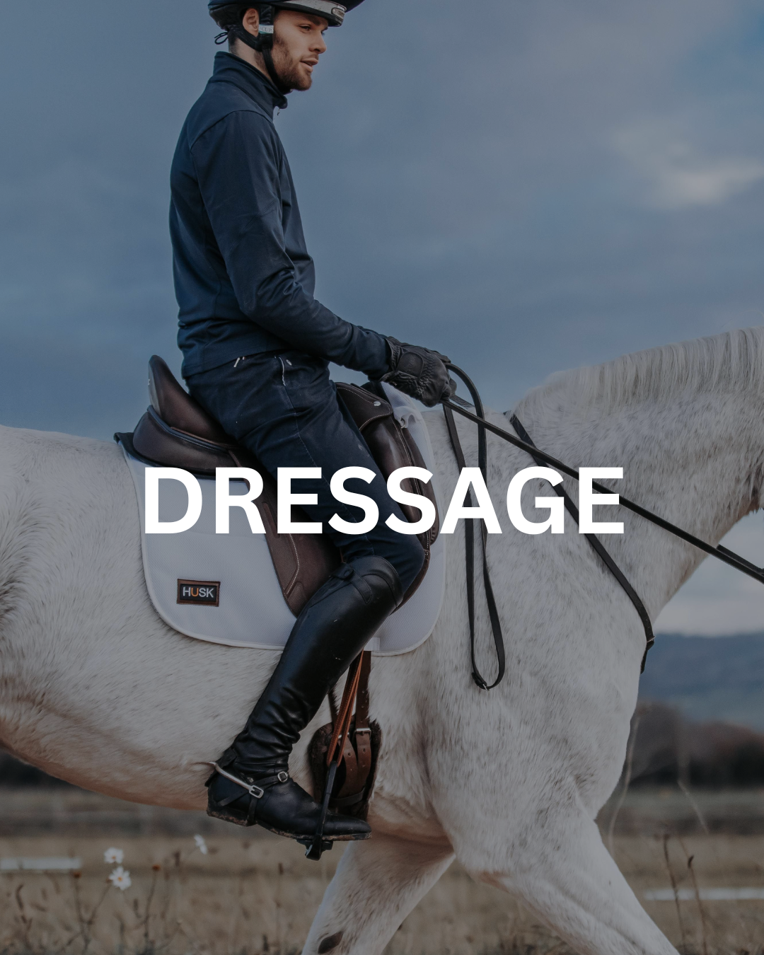 Man riding a white horse in dressage competition.