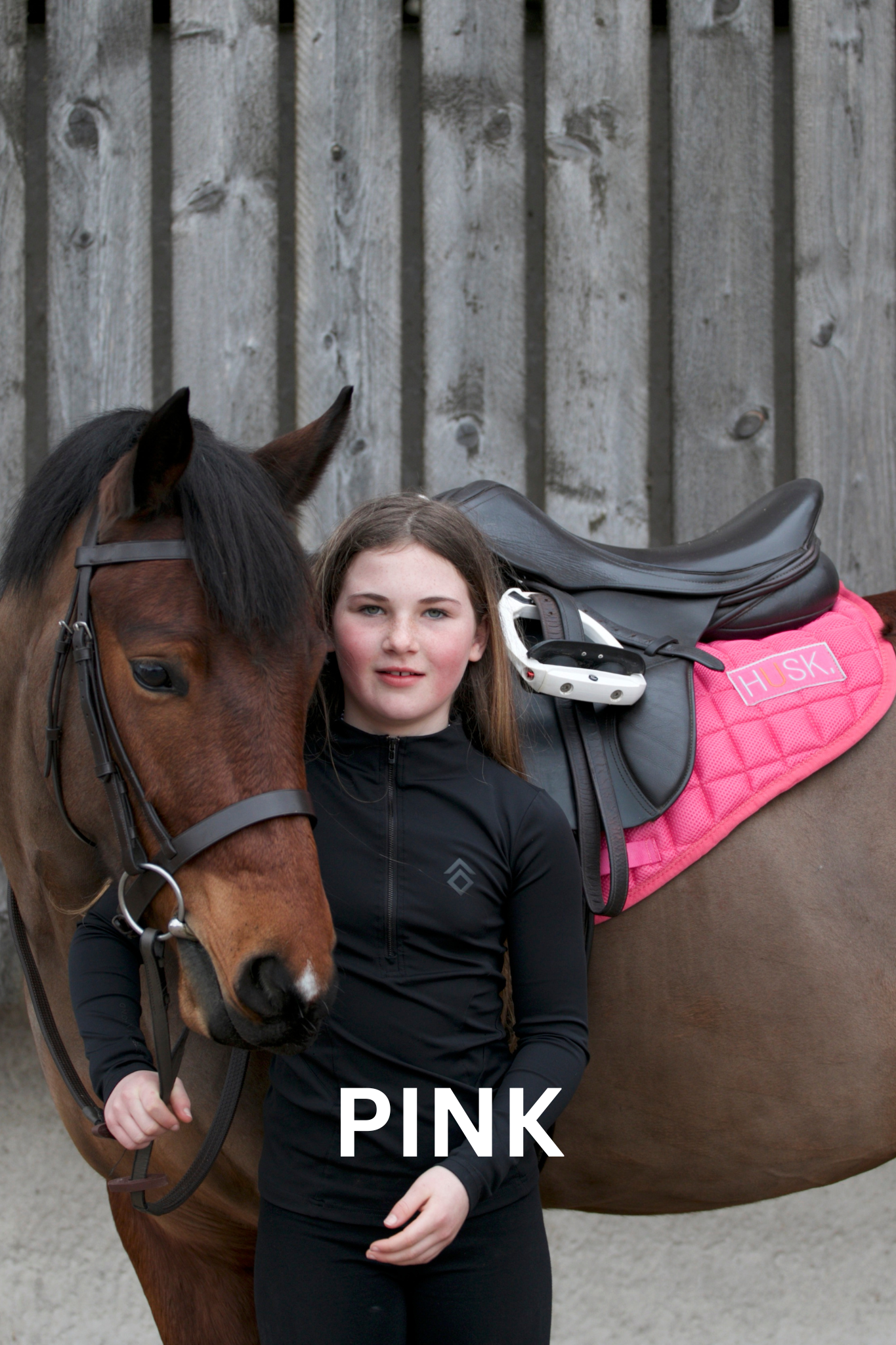 Girl in black riding clothes with horse wearing pink saddle pad.