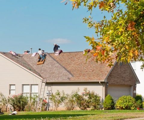 A group of people are working on the roof of a house
