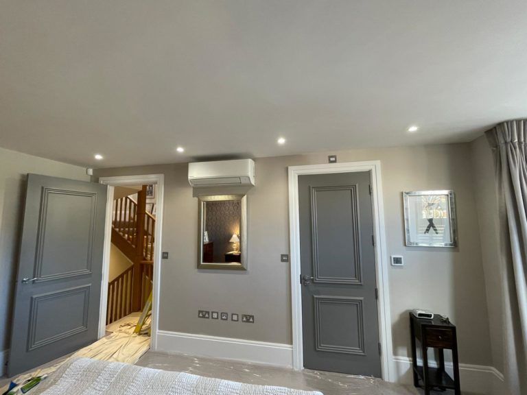 A bedroom with a bed , a mirror , and a clock on the wall.