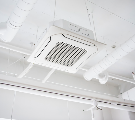 A white air conditioner is hanging from the ceiling of a building