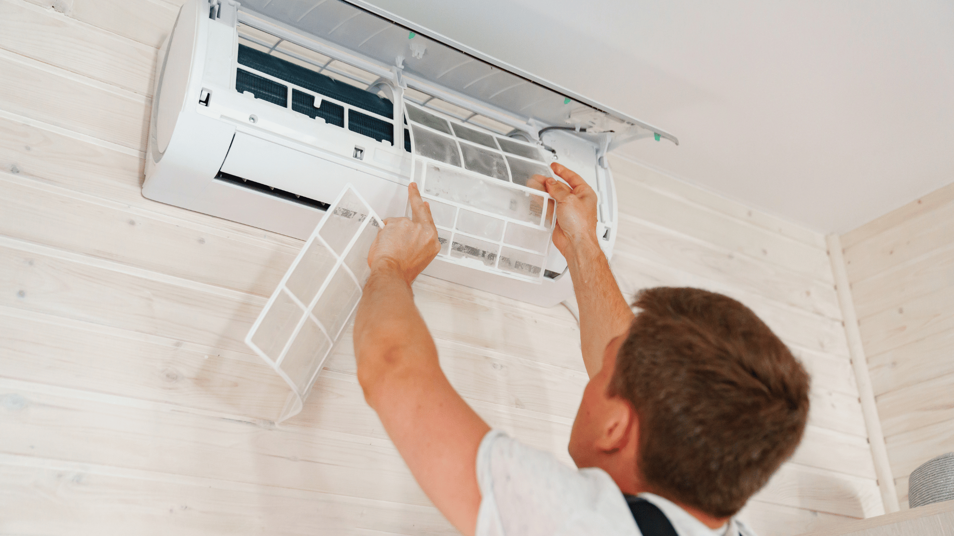 A man is cleaning the filter of an air conditioner.