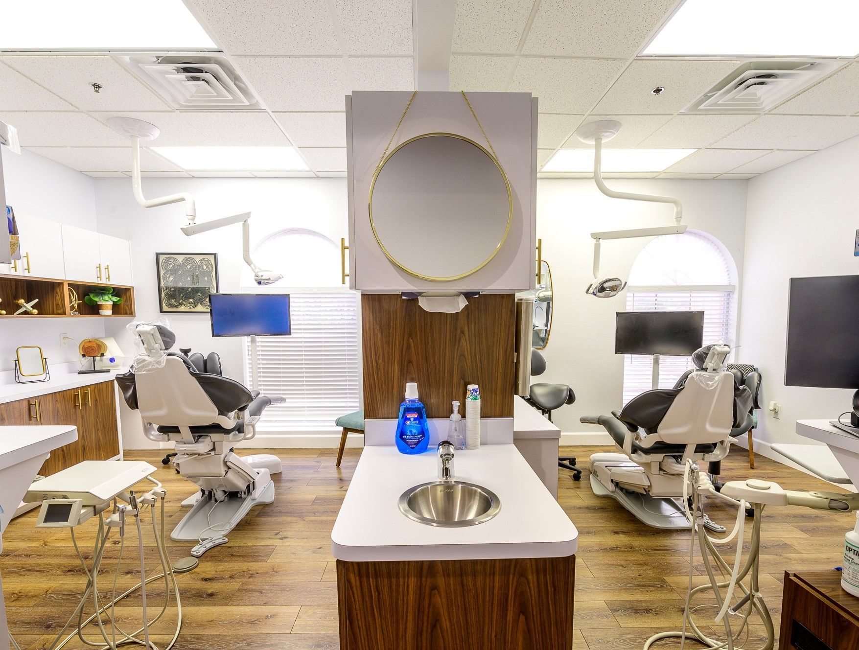 A dental office with lots of dental chairs and a sink.