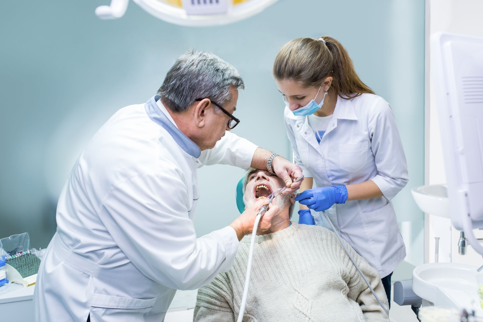 Dentist examining patient's teeth with assistant in a dental office.
