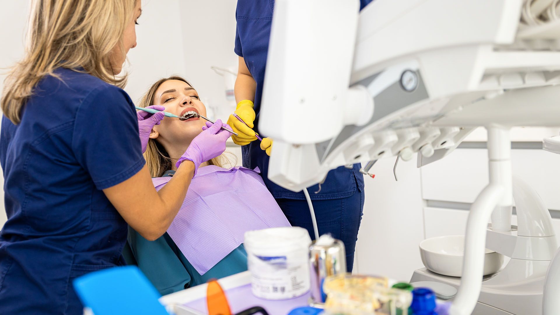 Dentist examining a patient's mouth with tools in a dental office.