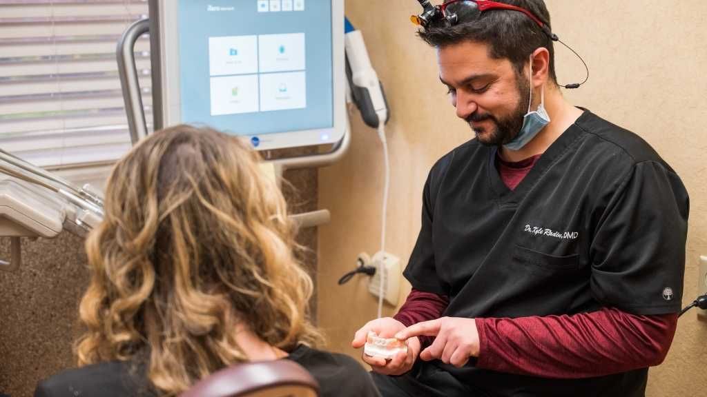 A dentist is talking to a patient in a dental office.