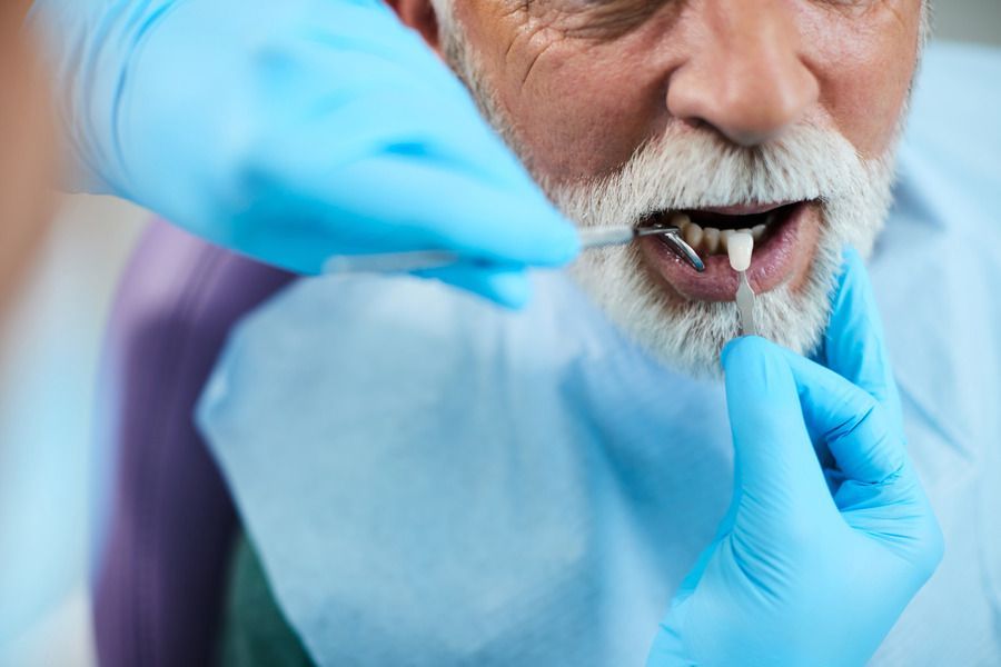 An elderly man is getting his teeth examined by a dentist.