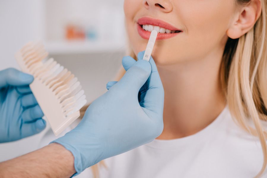 A woman is getting her teeth whitened by a dentist.