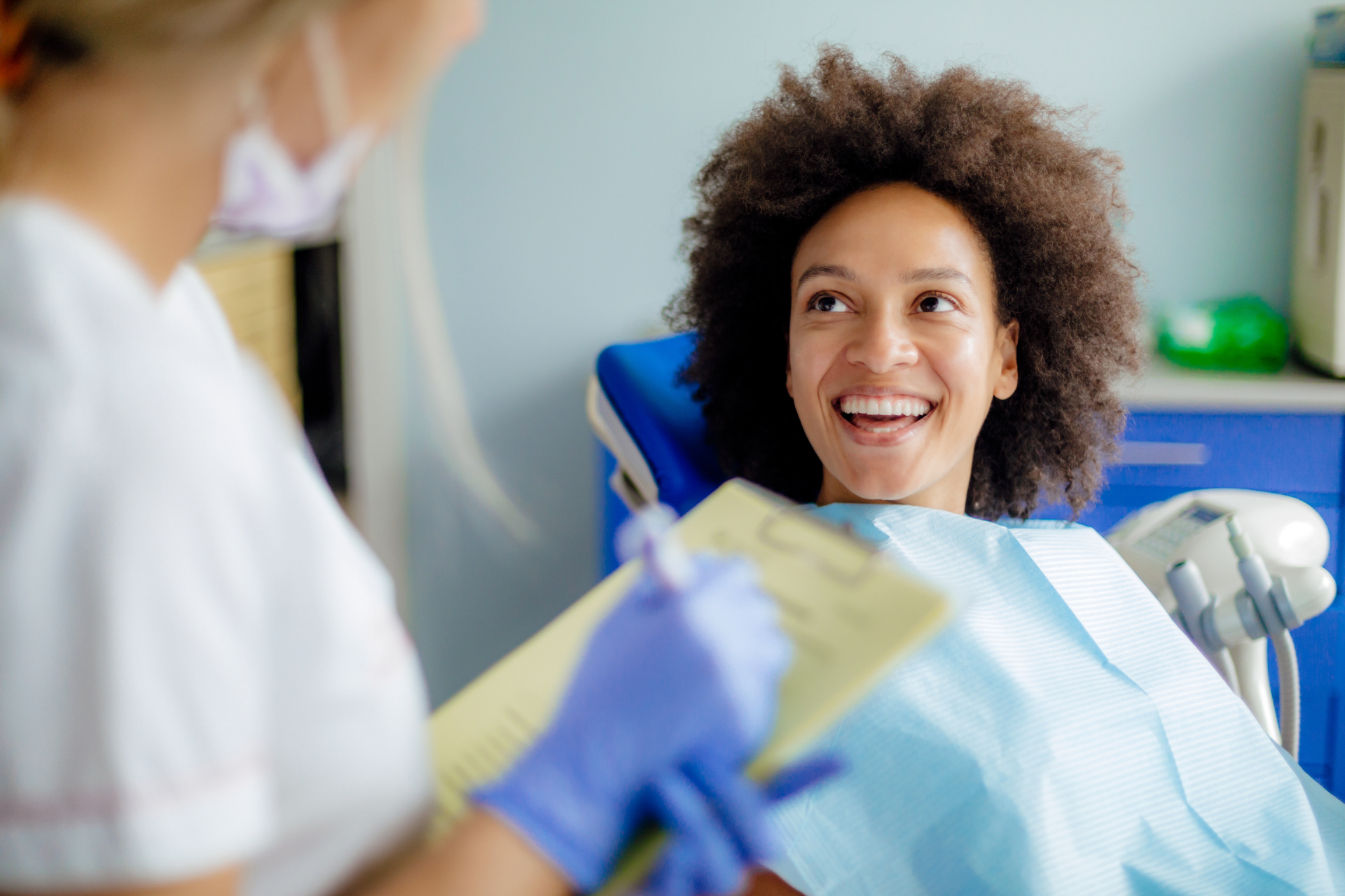 A woman is smiling while sitting in a dental chair.