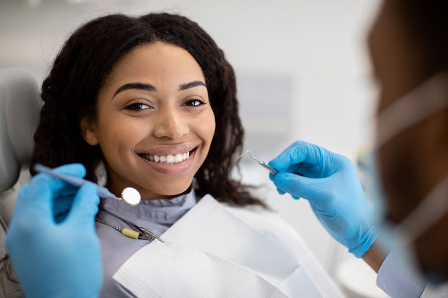 A woman is smiling while having her teeth examined by a dentist.