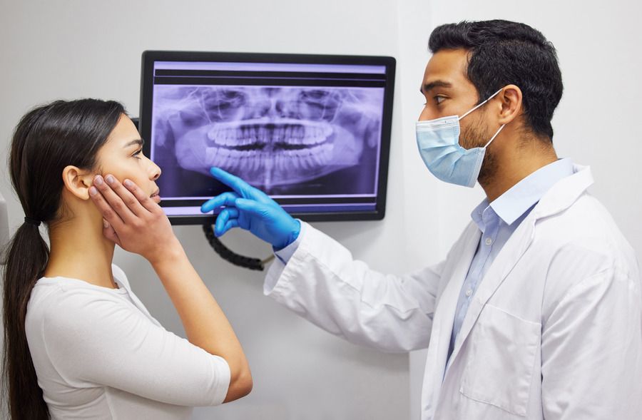 A dentist is looking at an x-ray of a patient 's teeth.