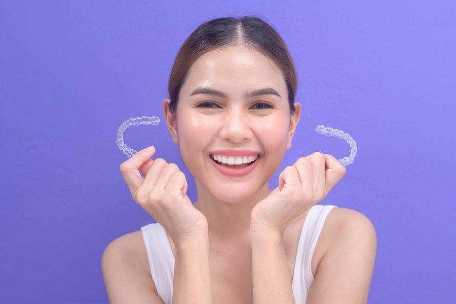 A woman is holding two clear braces in her hands and smiling.