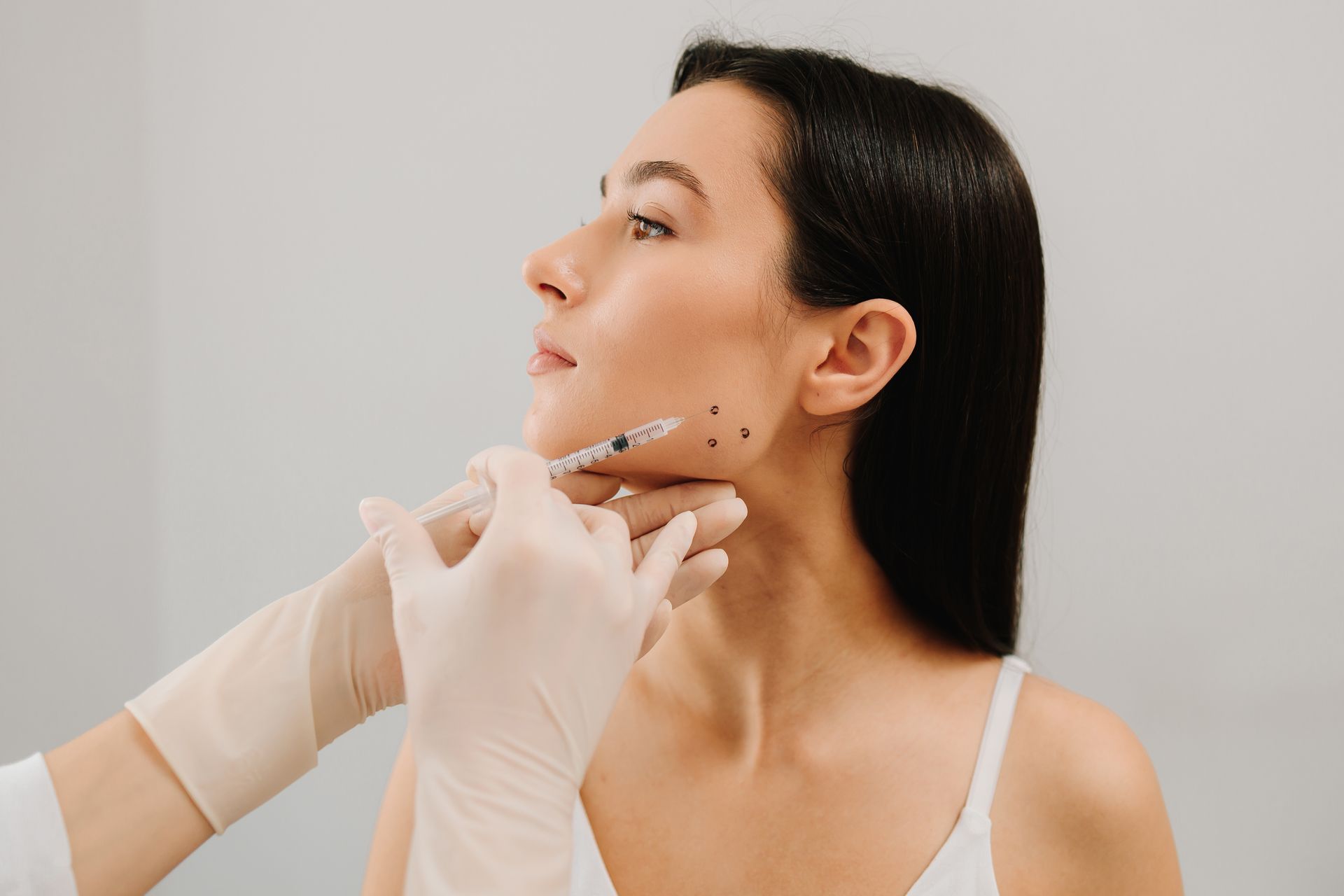 Person receiving facial injections in a medical setting.