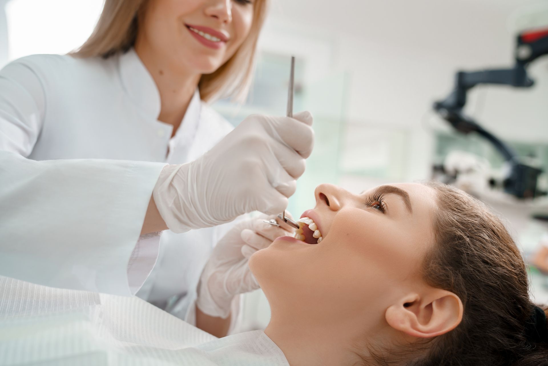 Dentist examining a patient's teeth with tools in a dental office setting.