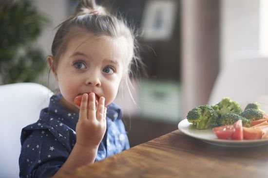 Una bambina che mangia verdure