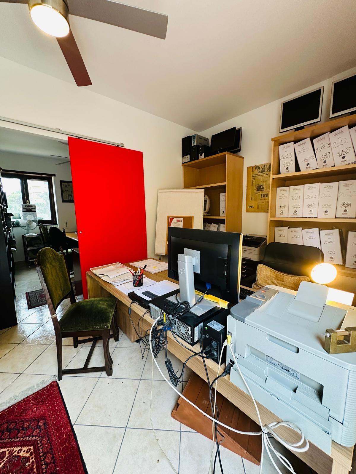 Una stanza con una scrivania, una sedia, una stampante e un computer