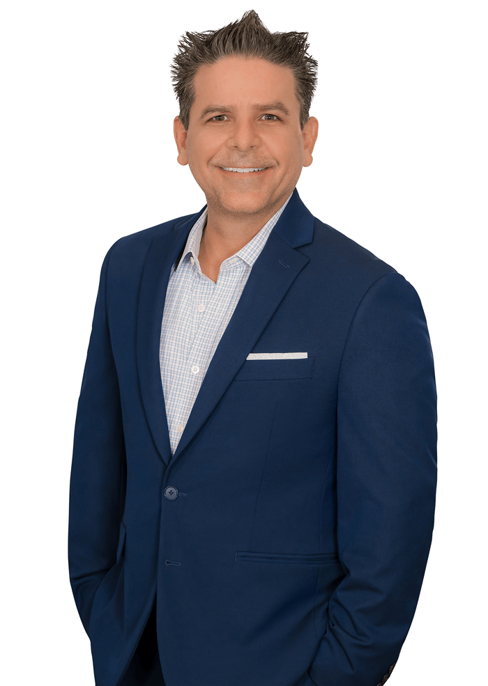 Man in blue blazer smiling, hands in pockets.