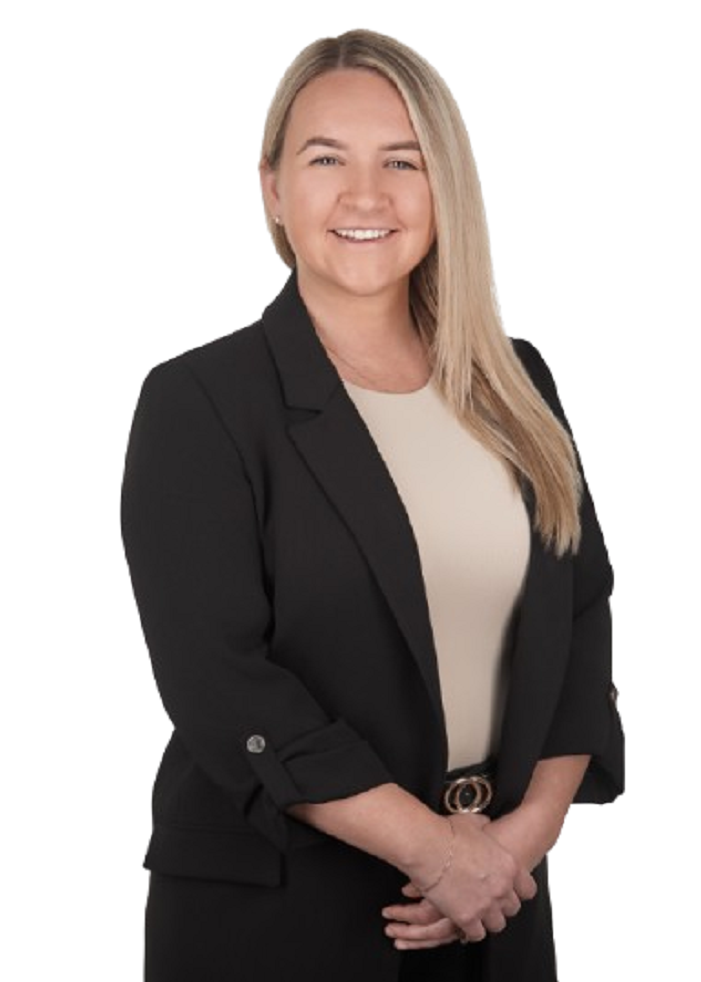 Woman with blonde hair, smiling, wearing a black blazer and tan shirt, arms crossed.