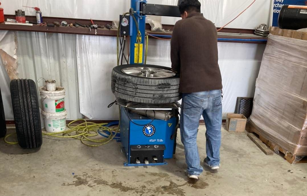 Man working on a tire with a machine in a garage.