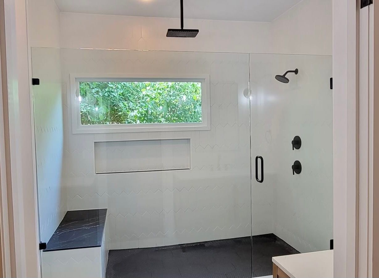A bathroom with a walk in shower and a window.