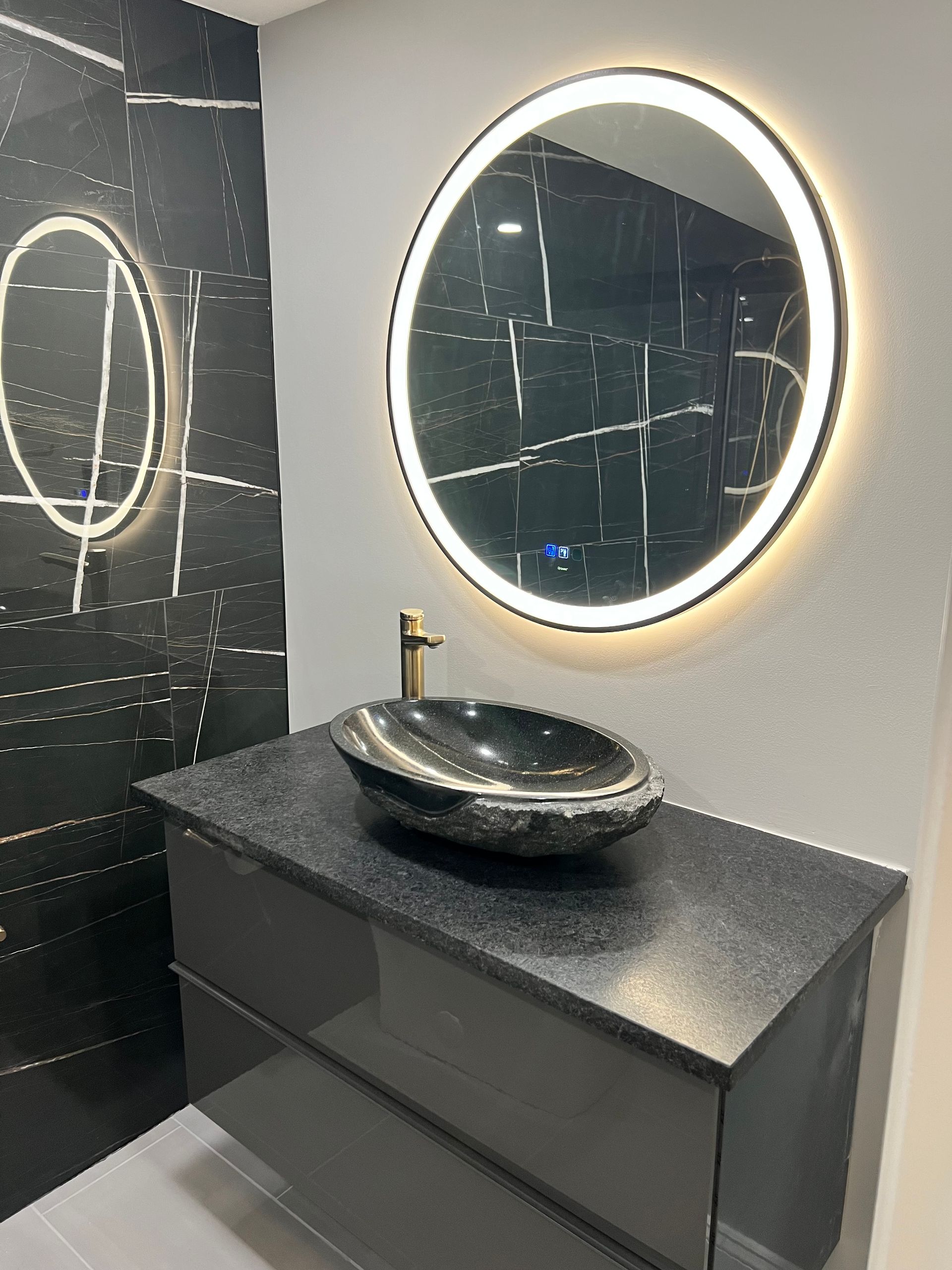 A bathroom with a sink and a round mirror