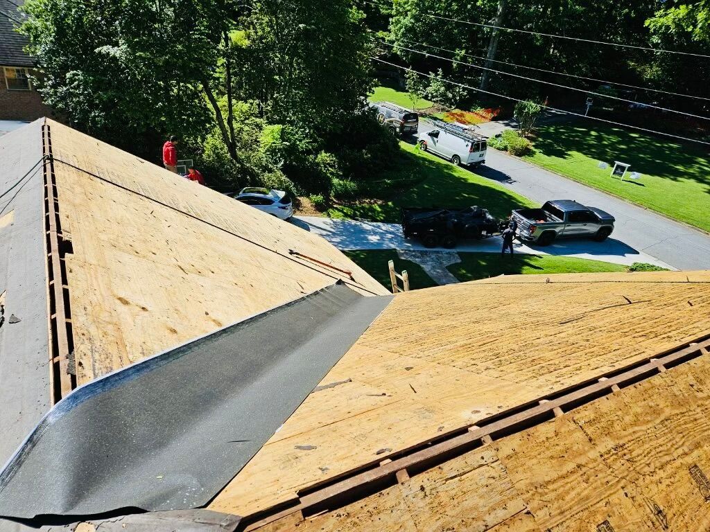 An aerial view of a roof under construction with a truck parked in the driveway.