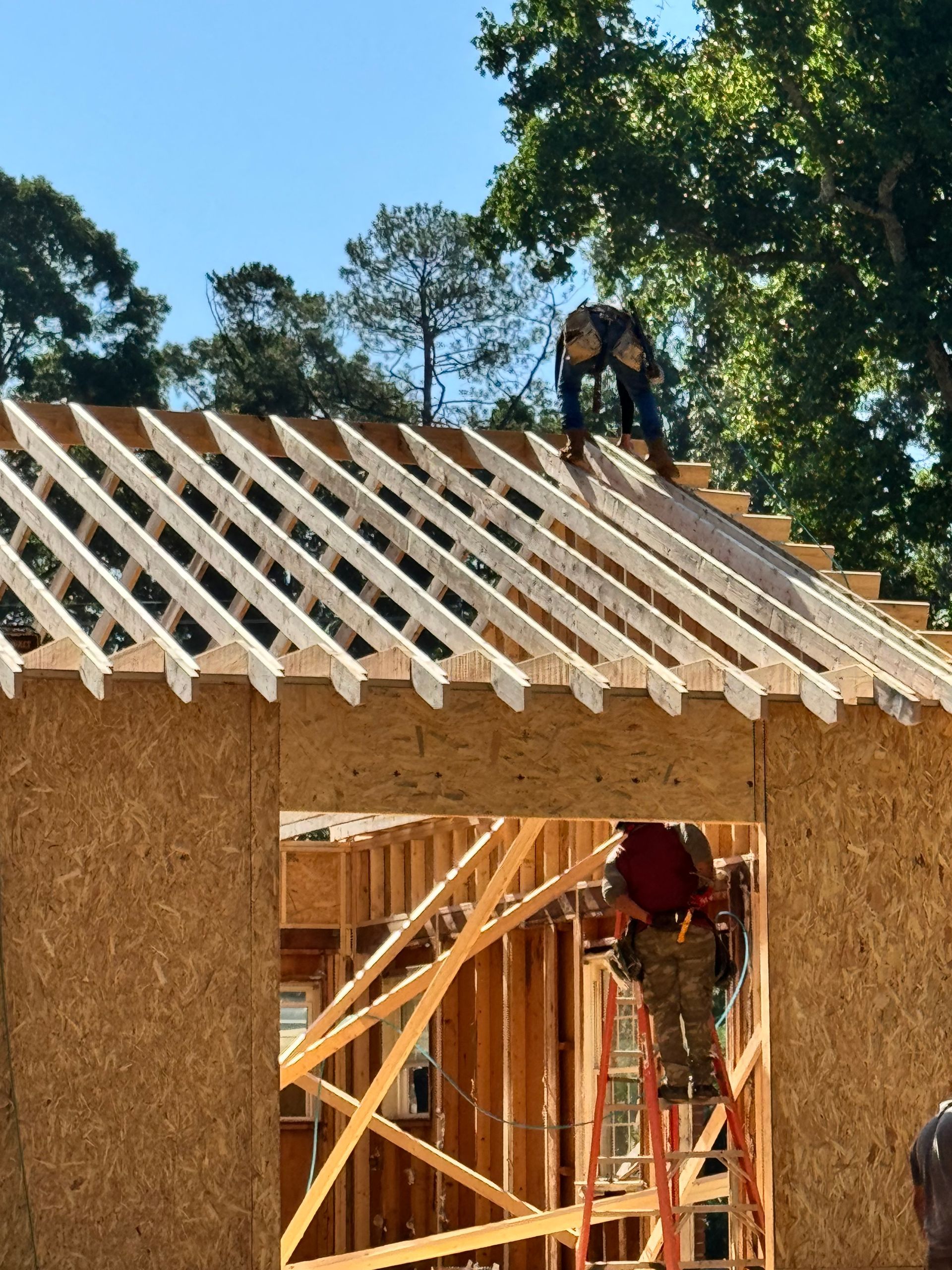 A man is working on the roof of a house under construction.