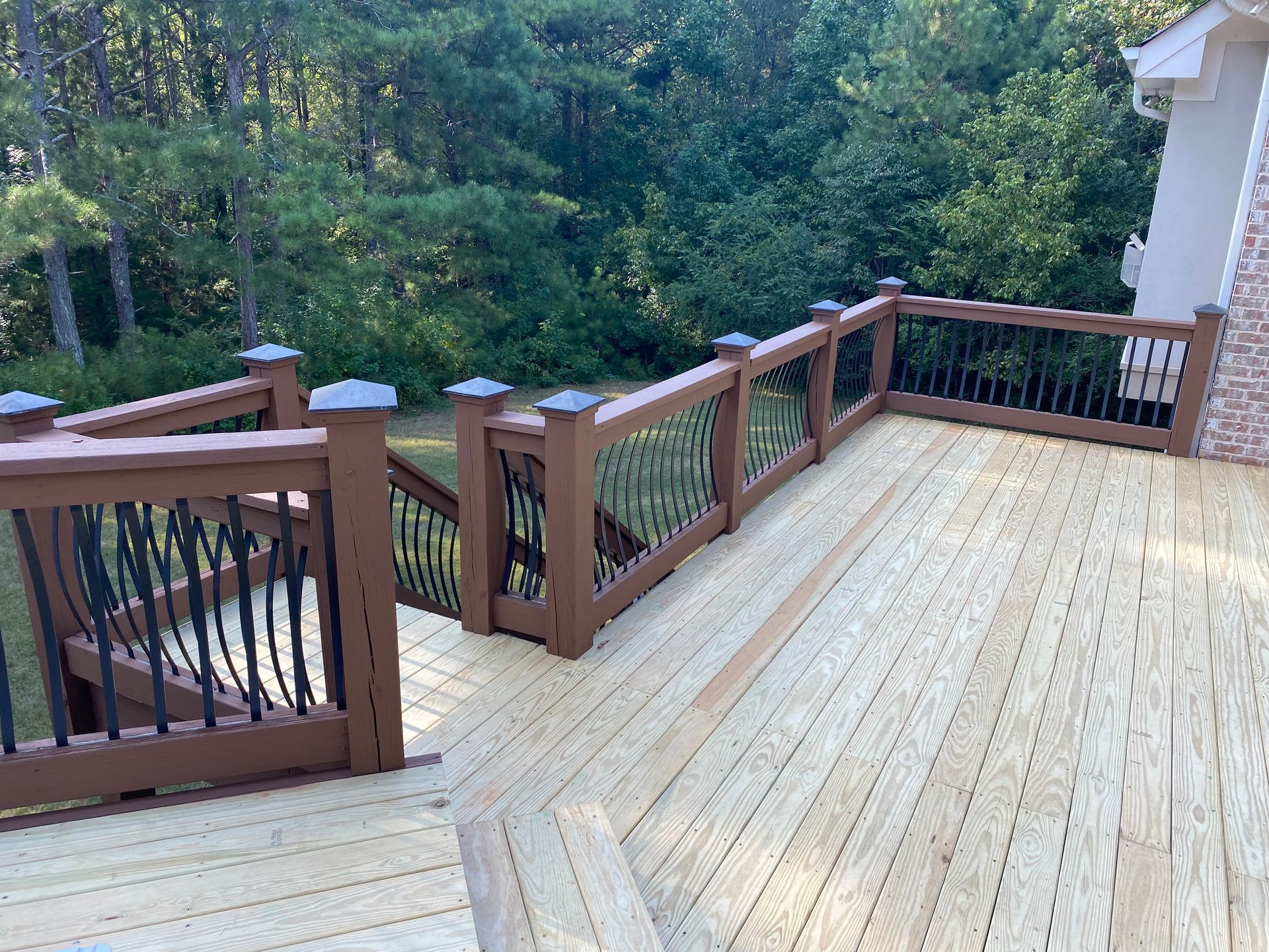 A wooden deck with stairs leading up to it and trees in the background.