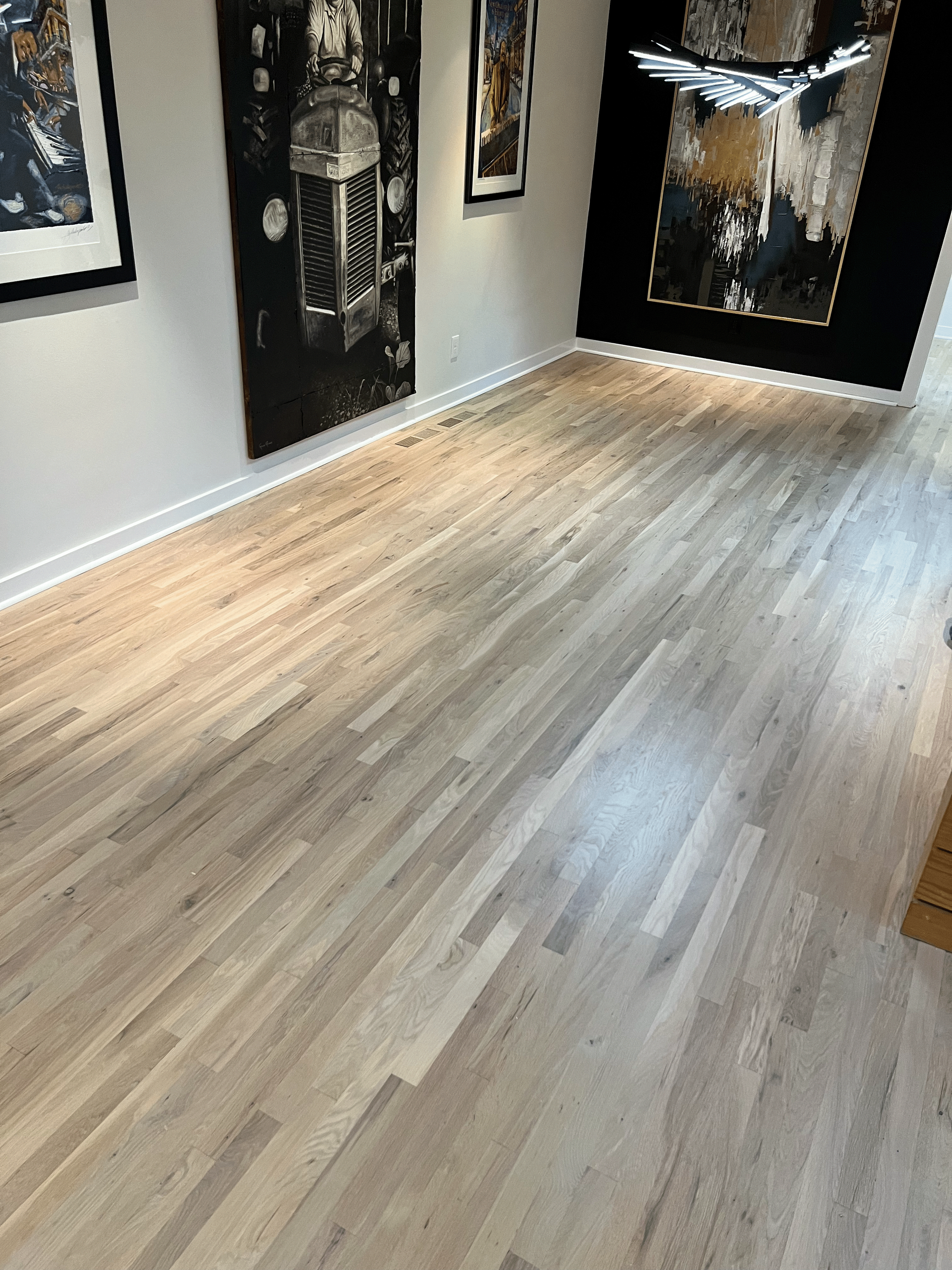 A room with a wooden floor and paintings on the walls.