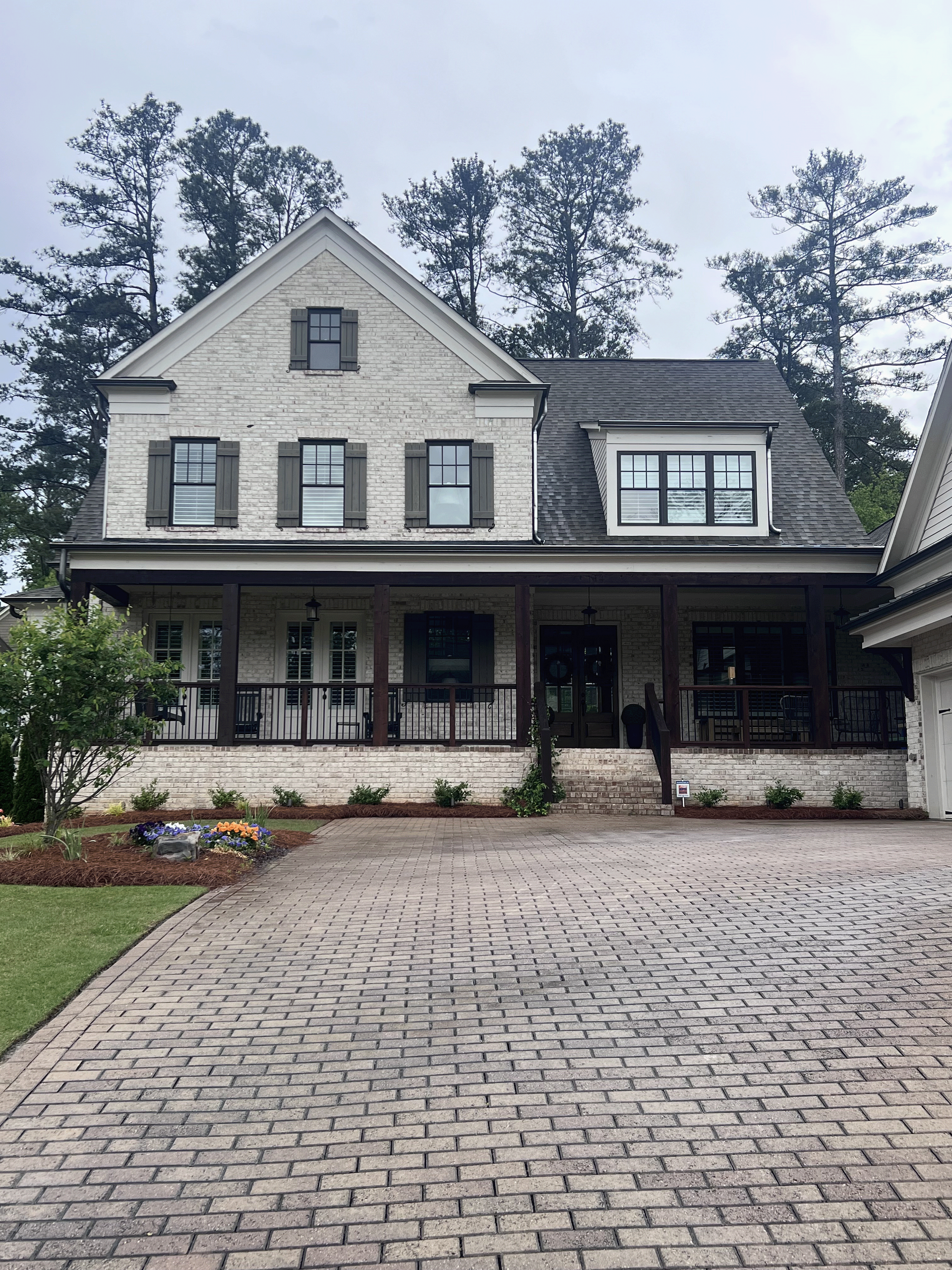 A large white brick house with a brick driveway in front of it.