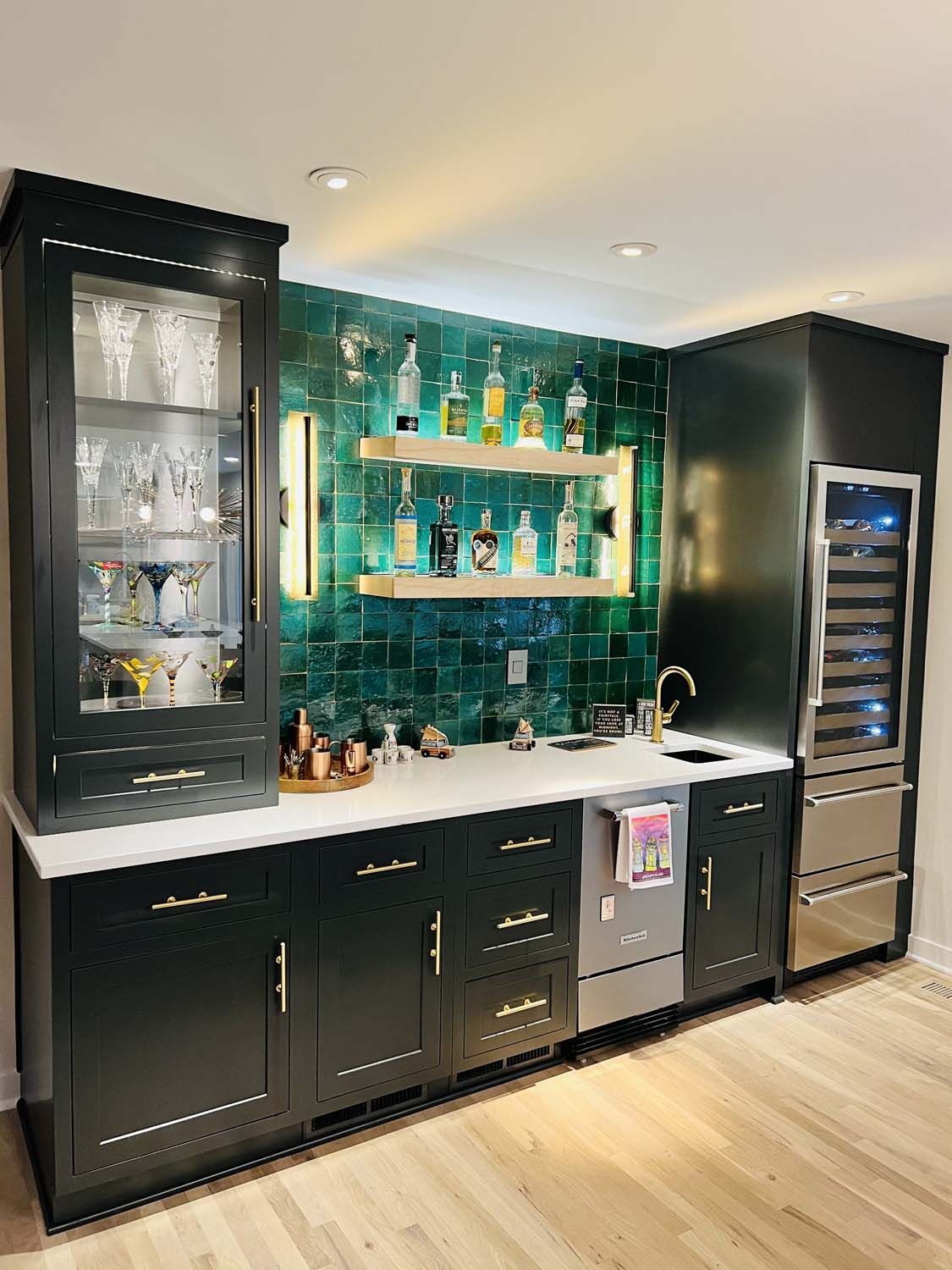 A kitchen with black cabinets and stainless steel appliances and a bar.