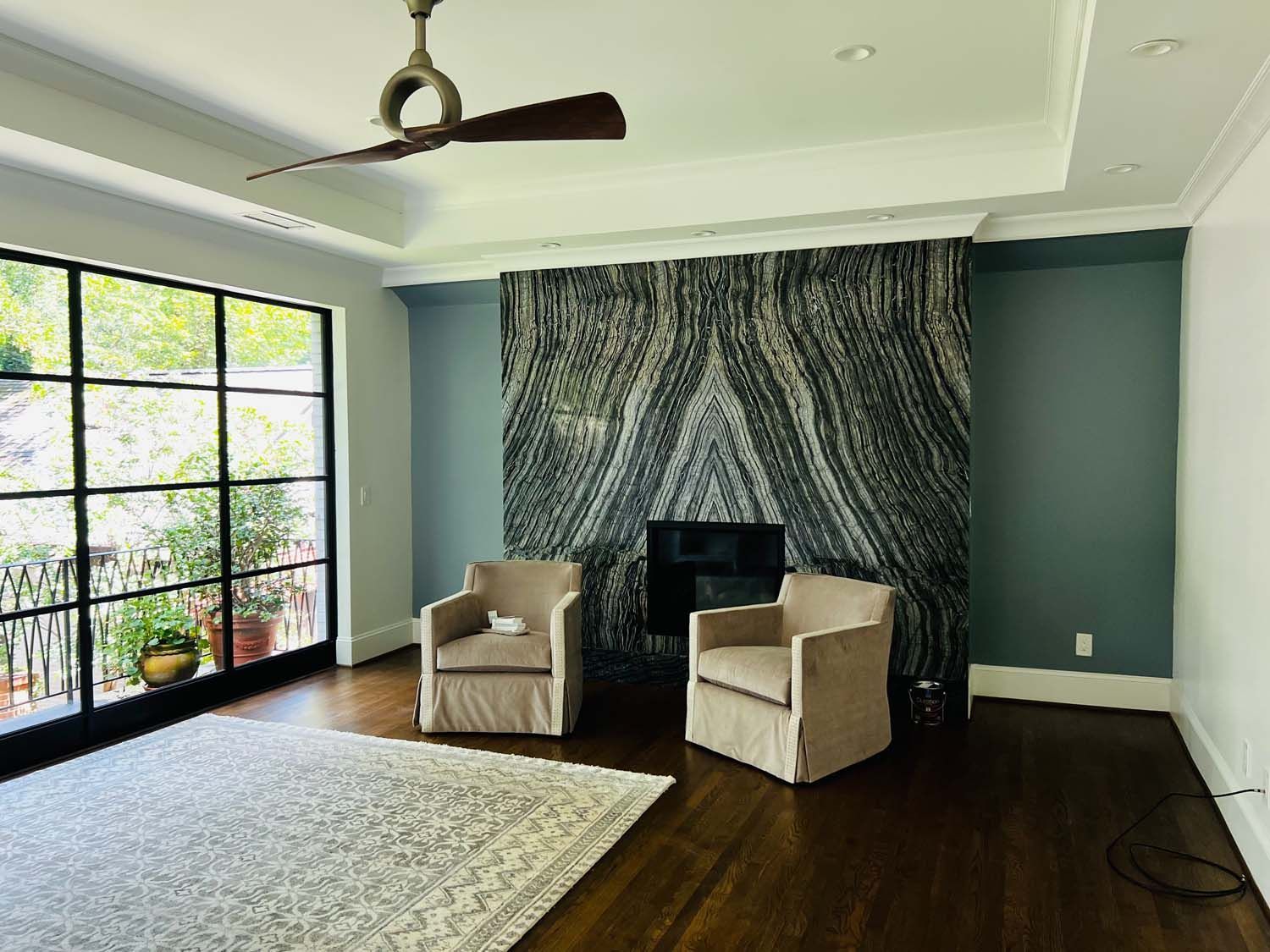 A living room with two chairs , a fireplace and a ceiling fan.
