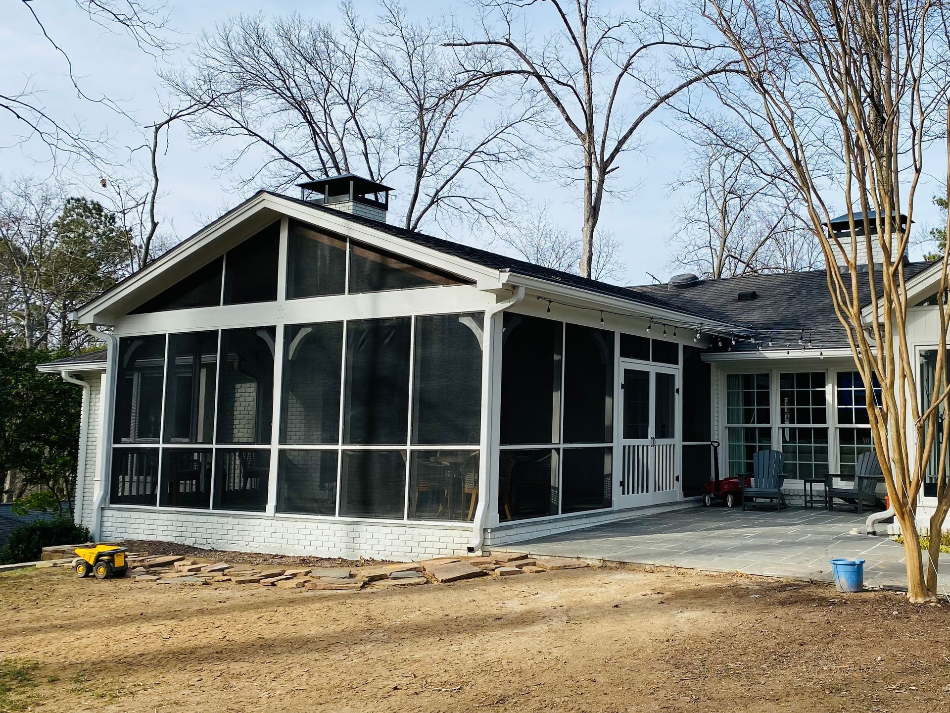 A screened in porch in the backyard of a house