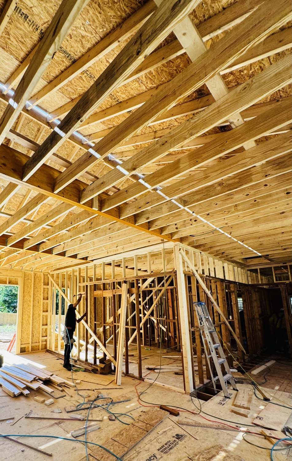 A man is standing in the middle of a house under construction.
