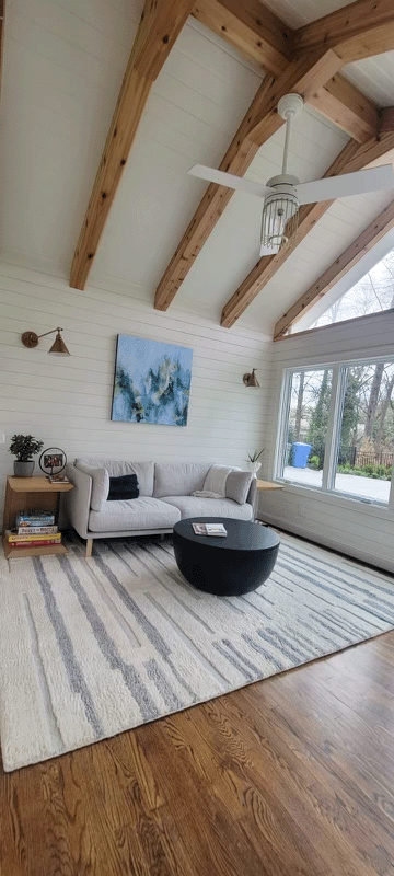 A living room with a couch , coffee table , rug and ceiling fan.