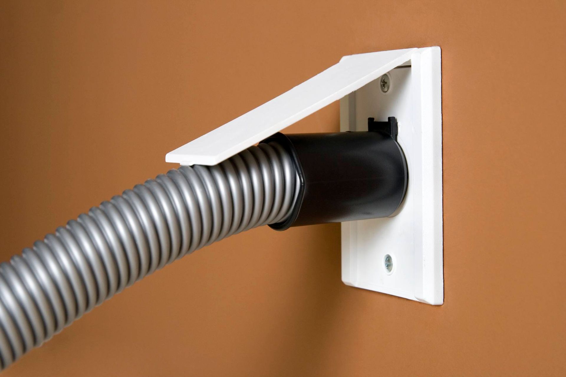 A vacuum hose is attached to a wall outlet