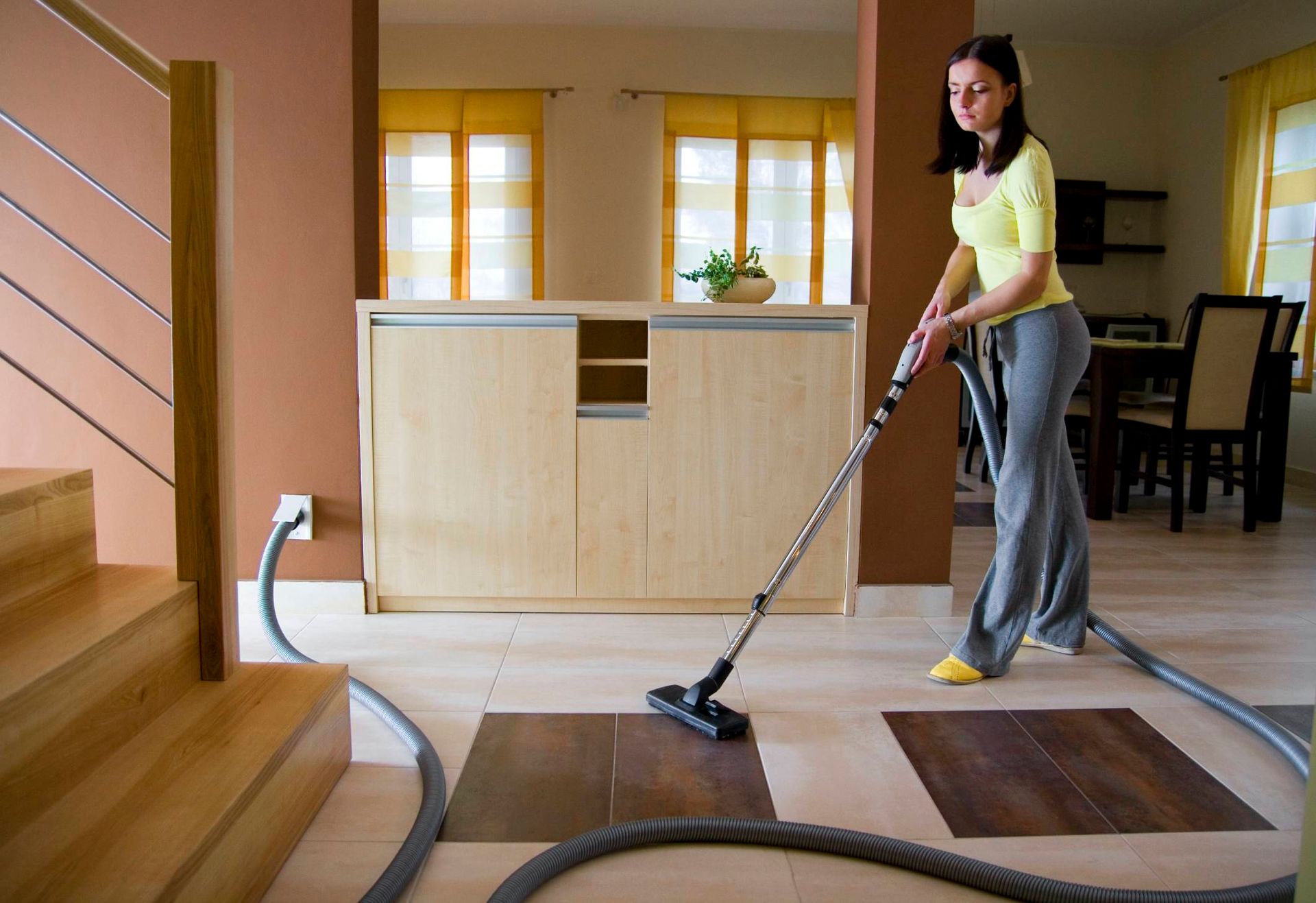 A woman is vacuuming the floor in a living room