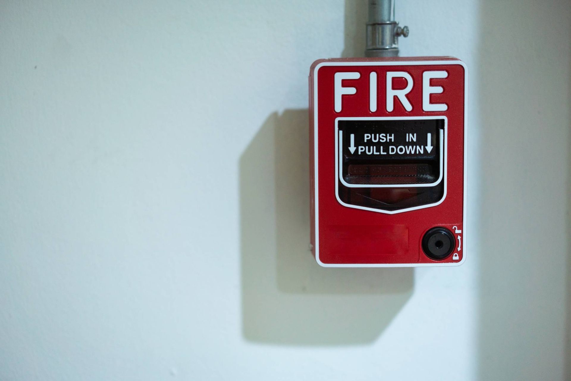 A red fire alarm is hanging on a white wall