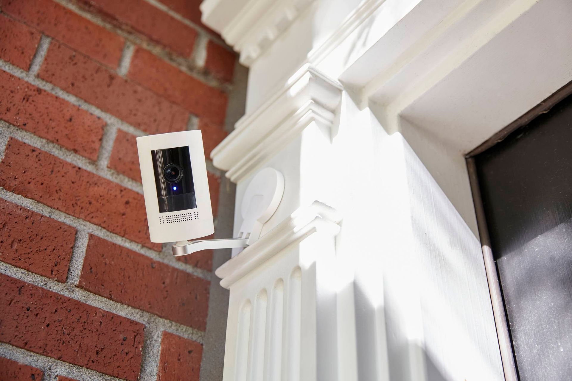 A security camera is mounted on the side of a brick building