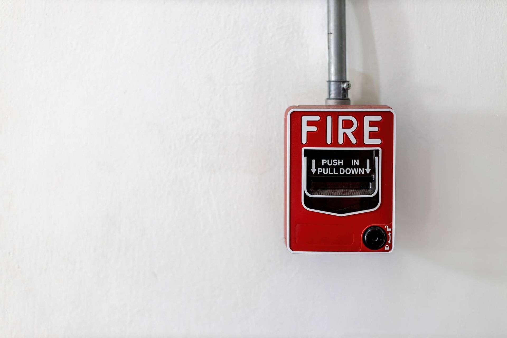 A red fire alarm is hanging on a white wall