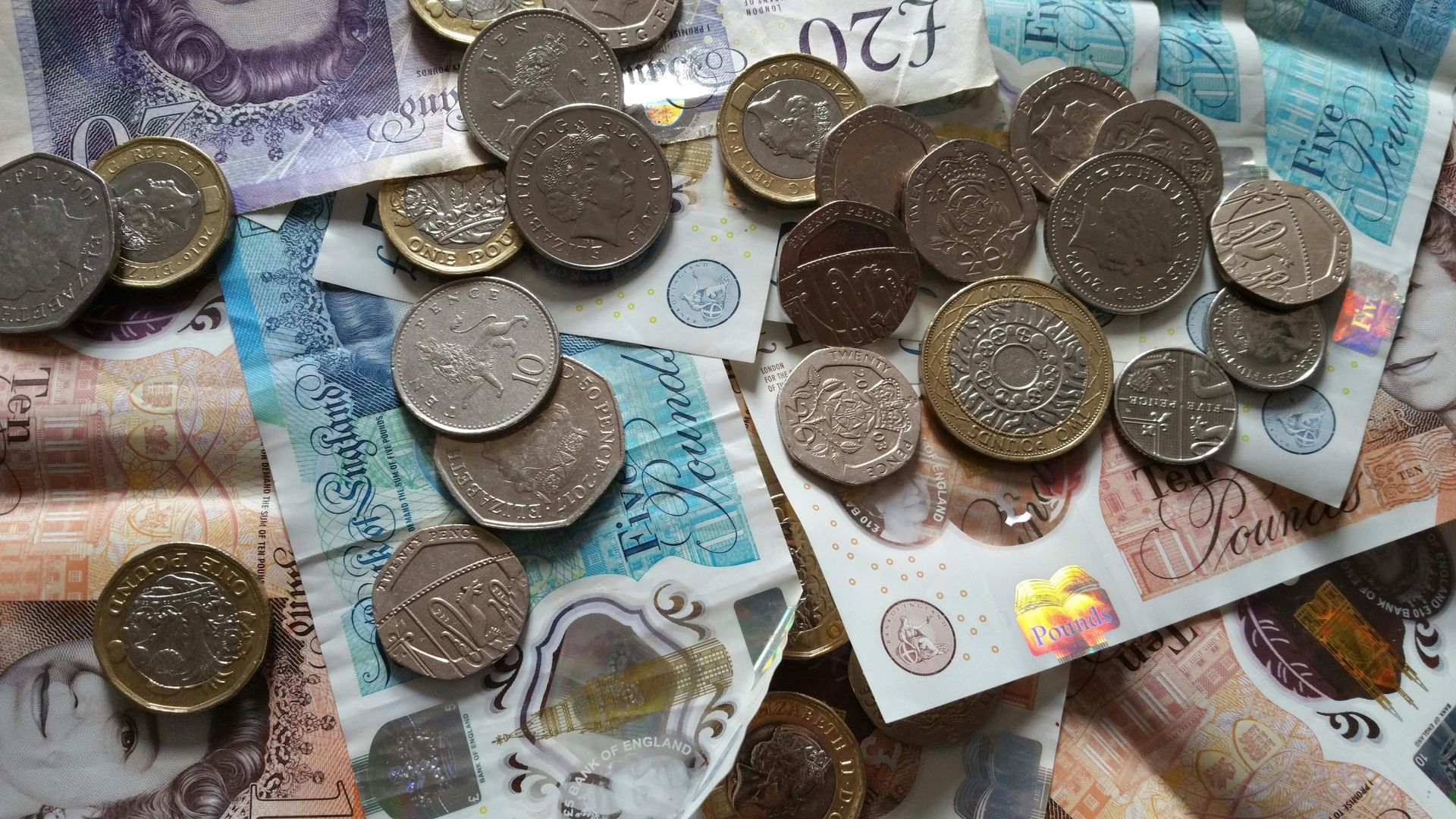 A pile of money and coins including a 20 pound note