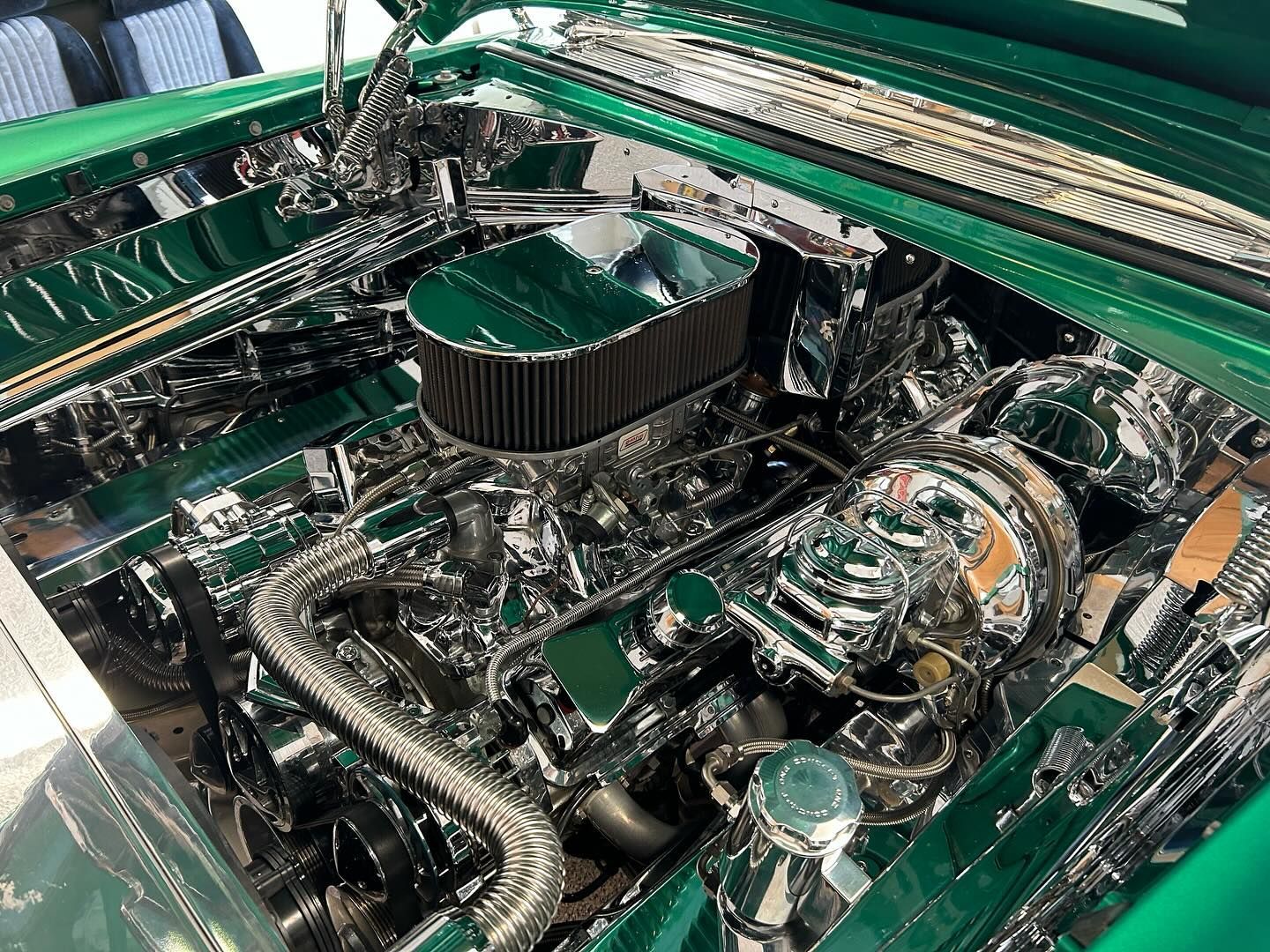 The engine of a green car is shown with the hood open.