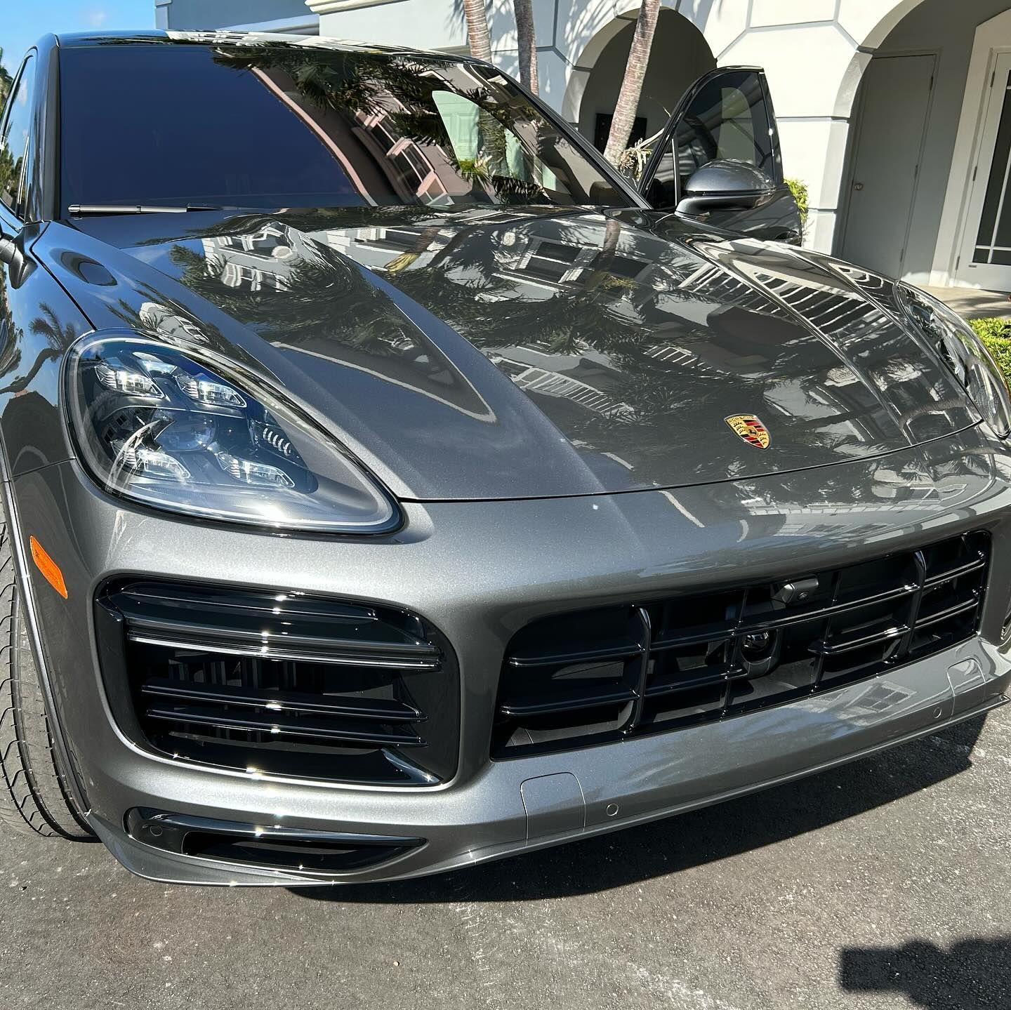 A gray porsche cayenne turbo is parked in front of a building.
